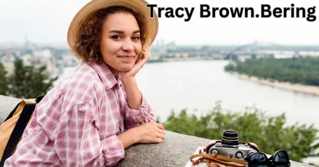 a person in a hat leaning on a ledge with a camera and a river tracy brown.bering